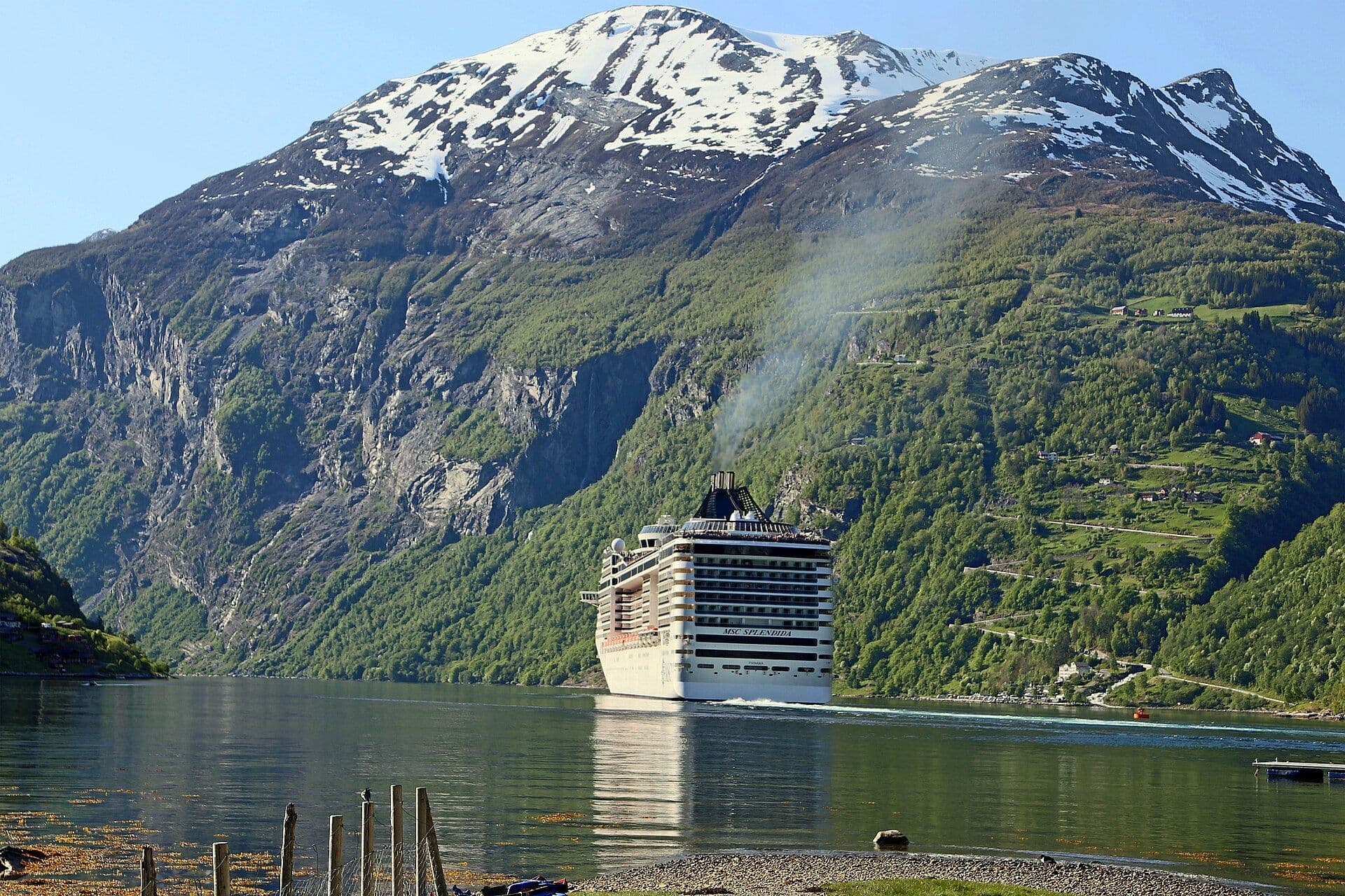 A cruise ship in Norway's Geirangerfjord beneath snow-capped peaks