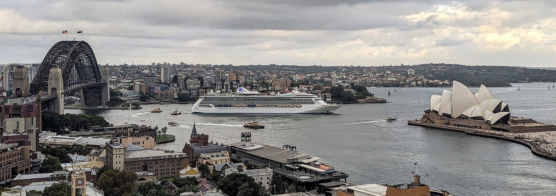 A cruise ship sailing past the Sydney Opera House and Harbour Bridge